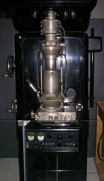Rplica del microscopio de 1933. Primer microscopio electrnico con un poder de resolucin superior al de un microscopio ptico. Por primera vez, el aparato tena un condensador delante de la muestra y dos lentes de aumento. Lograba una ampliacin de 12000 veces.