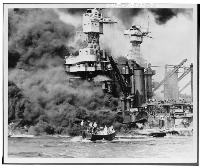 Pearl Harbor, Hawi. Un bote pequeo rescata a un marinero del USS West Virginia (BB-48) de 31.800 toneladas, que se quema en primer plano. El humo que se extiende en medio del barco muestra dnde ocurri el dao ms extenso. Observe a los dos hombres en el superestructura. El USS Tennessee (BB-43) est dentro